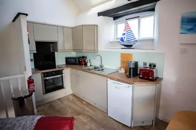 a small kitchen with white cabinets and a red appliance at Treworgie Barton - Butterwell in Bude