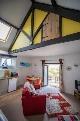 a living room with a red couch and a kitchen at Treworgie Barton - Butterwell in Bude