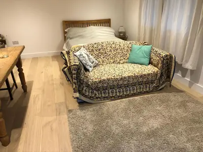 a living room with a couch and a bed at Apple Tree Barn - converted barn with meadow views in Helston