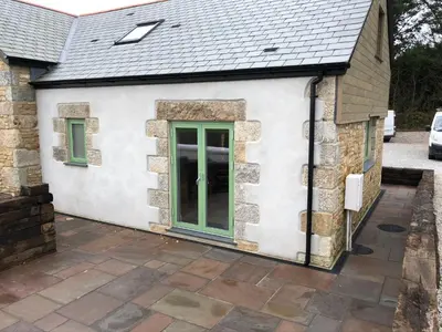 a house with a green door on the side of it at Apple Tree Barn - converted barn with meadow views in Helston