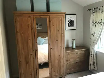 a wooden cabinet in a bedroom with a bed at No 63 Atlantic reach in Newquay