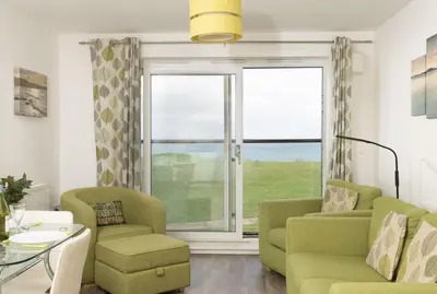 a living room with a couch and chairs and a window at 17 Astor Court, Newquay in Newquay