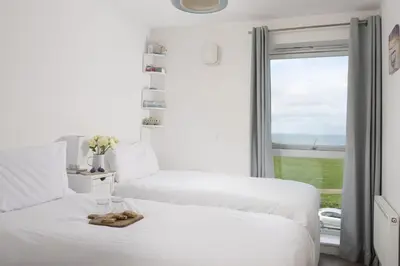 two beds in a room with a window at 17 Astor Court, Newquay in Newquay