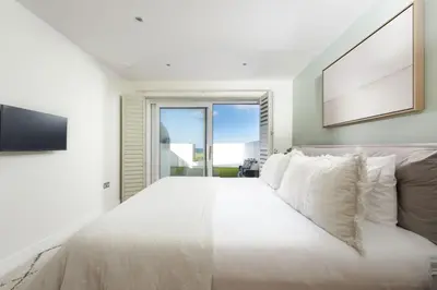 a white bedroom with a large bed and a window at 66 Pentire, Newquay in Newquay