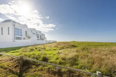 a white house on top of a grassy hill at 66 Pentire, Newquay in Newquay