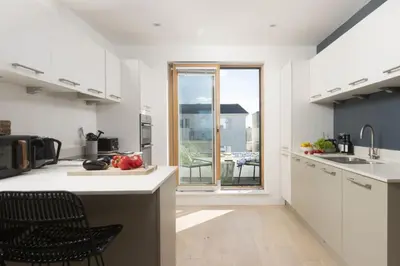 a kitchen with white cabinets and a table with fruits at 66 Pentire, Newquay in Newquay