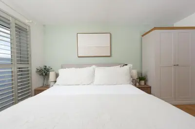 a white bedroom with a large white bed at 66 Pentire, Newquay in Newquay