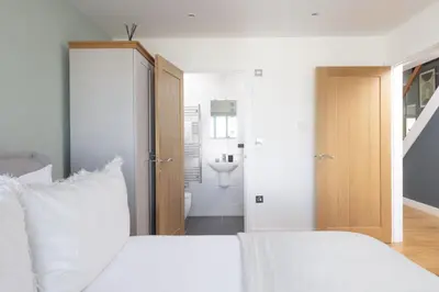 a bedroom with a white bed and a bathroom at 66 Pentire, Newquay in Newquay