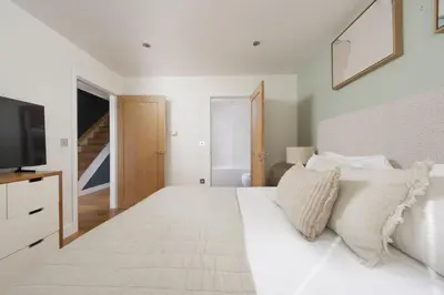 a bedroom with a large white bed with a television at 66 Pentire, Newquay in Newquay