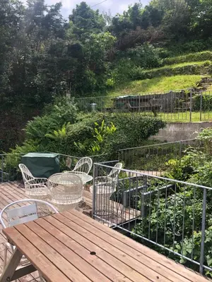a deck with a table and chairs and a garden at Crows Nest Apartment, at Clipper House with free onsite allocated parking in Looe