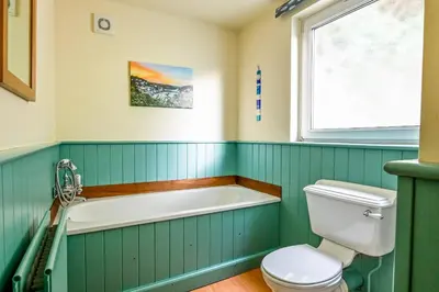 a bathroom with a bath tub and a toilet at Crows Nest Apartment, at Clipper House with free onsite allocated parking in Looe