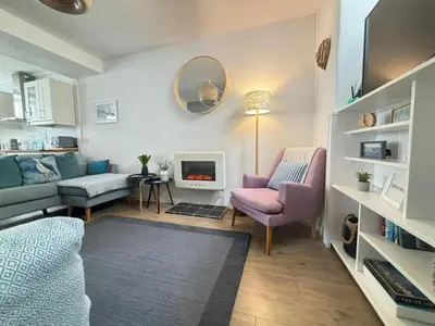 a living room with a couch and a tv at Sandy Feet, St Eia Street. Cosy Cottage + Parking in St Ives