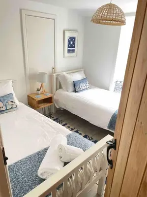 a bedroom with two beds and a table with a lamp at Sandy Feet, St Eia Street. Cosy Cottage + Parking in St Ives
