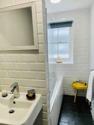 a white bathroom with a sink and a bath tub at Sandy Feet, St Eia Street. Cosy Cottage + Parking in St Ives