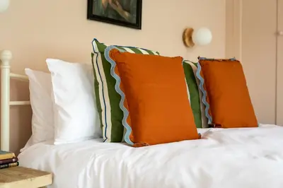 a bed with orange and green pillows on it at no.five Flushing in Flushing