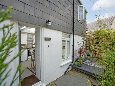 a house with a white door and a patio at Spa Cottage in Mevagissey