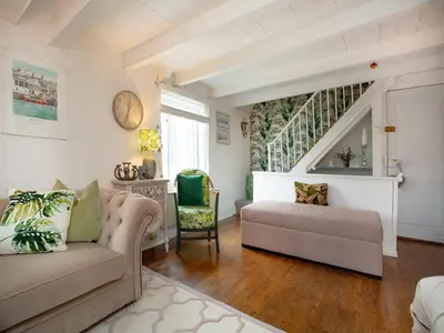 a living room with a couch and a staircase at Spa Cottage in Mevagissey