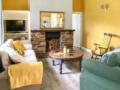 a living room with a table and a fireplace at The Old Bakehouse in Perranporth