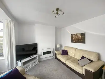 a living room with a couch and a flat screen tv at Glenview in Perranporth