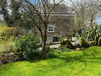 a stone house with a tree in a yard at Cottage hideaway on the edge of Bodmin Moor in Launceston