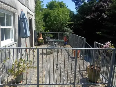 a balcony with an umbrella and a table and chairs at Cottage hideaway on the edge of Bodmin Moor in Launceston