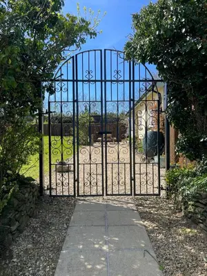 a gate to a garden with a playground behind it at Honeycomb Cottage - a quiet, charming, cosy retreat in the countryside only 2 miles from one of Cornwall's best beaches in Truro