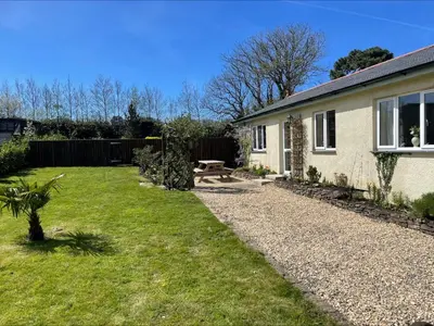 a backyard of a house with a grass yard at Honeycomb Cottage - a quiet, charming, cosy retreat in the countryside only 2 miles from one of Cornwall's best beaches in Truro