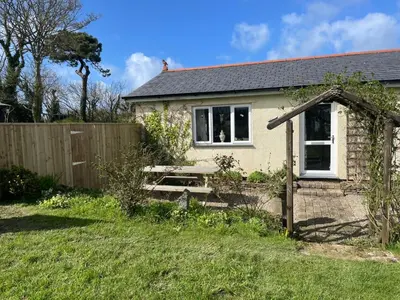 a small house with a picnic table in a yard at Honeycomb Cottage - a quiet, charming, cosy retreat in the countryside only 2 miles from one of Cornwall's best beaches in Truro