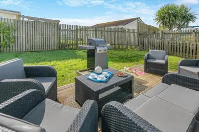 a patio with chairs and a grill on a deck at 3 Bed in St. Merryn oc-l29062 in St Merryn