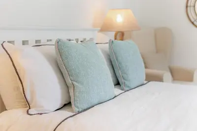 a bed with three pillows on it with a chair at 2 Bed in Fowey oc-m29077 in Fowey
