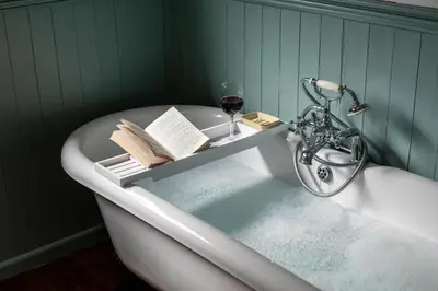 a bath tub with a book and a glass of wine at 5 Bed in Little Petherick oc-s29057 in Little Petherick