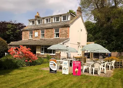 a house with tables and umbrellas in front of it at Elerkey Guest House in Veryan