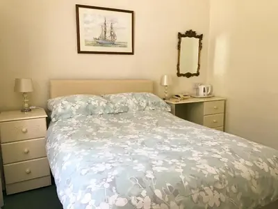 a bedroom with a bed and a dresser and a mirror at Elerkey Guest House in Veryan