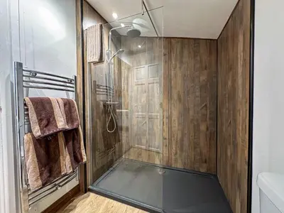 a bathroom with a shower with a glass door at Treetops Lodge, private Cornish hideaway, parking, garden in Truro