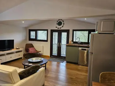 a kitchen and living room with a couch and a refrigerator at Treetops Lodge, private Cornish hideaway, parking, garden in Truro