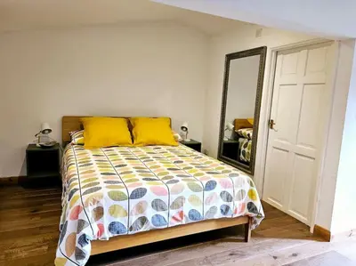 a bedroom with a bed with yellow pillows and a mirror at Treetops Lodge, private Cornish hideaway, parking, garden in Truro