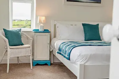 a bedroom with a bed and a chair and a window at 3 Bed in Treknow oc-h29194 in Treknow