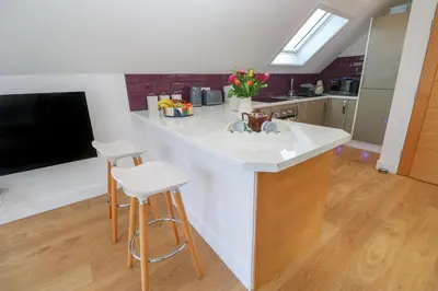 a kitchen with a sink and a counter with stools at Cuckoo's Rest in Penryn
