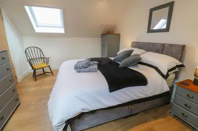 a bedroom with a large bed and a chair at Cuckoo's Rest in Penryn