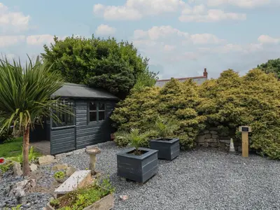 a garden with a black shed and some plants at Cuckoo's Rest in Penryn