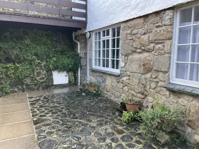 a stone house with a stone walkway next to a building at 3 Redfern Court in St Ives
