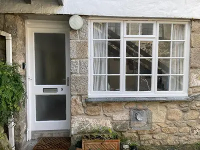 a stone house with a white door and a window at 3 Redfern Court in St Ives