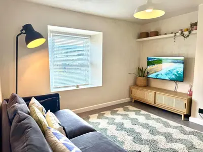 a living room with a couch and a flat screen tv at Palms 2 Private Garden Parking Central Newquay in Newquay