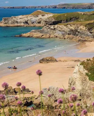 a beach with people in the water and a boat at Palms 2 Private Garden Parking Central Newquay in Newquay