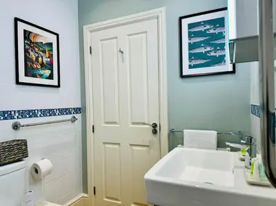 a bathroom with a sink and a white door at Luxury Sea View Apartment with Multi Room Balcony And Private Onsite Parking Only 300M From the Beach in Looe