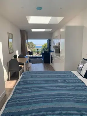 a bedroom with a bed and a kitchen with a view at Carbis Daze Ocean Views Studio, SuperKing bed St Ives Carbis Bay in Carbis Bay