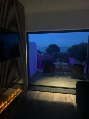 a room with a view of a patio with a table at Carbis Daze Ocean Views Studio, SuperKing bed St Ives Carbis Bay in Carbis Bay