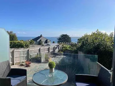 a patio with a table and a view of the ocean at Carbis Daze Ocean Views Studio, SuperKing bed St Ives Carbis Bay in Carbis Bay