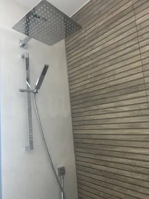 a bathroom with a wooden wall with a clock on the wall at Carbis Daze Ocean Views Studio, SuperKing bed St Ives Carbis Bay in Carbis Bay