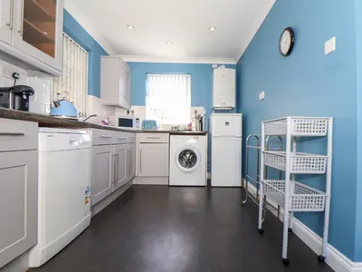a kitchen with blue walls and a washer and dryer at Flat 1 Niles Place in Padstow